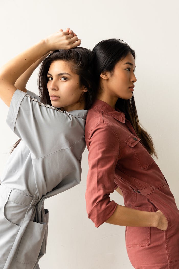services-02 Two women fashionably posing in colorful jumpsuits in a studio setting.